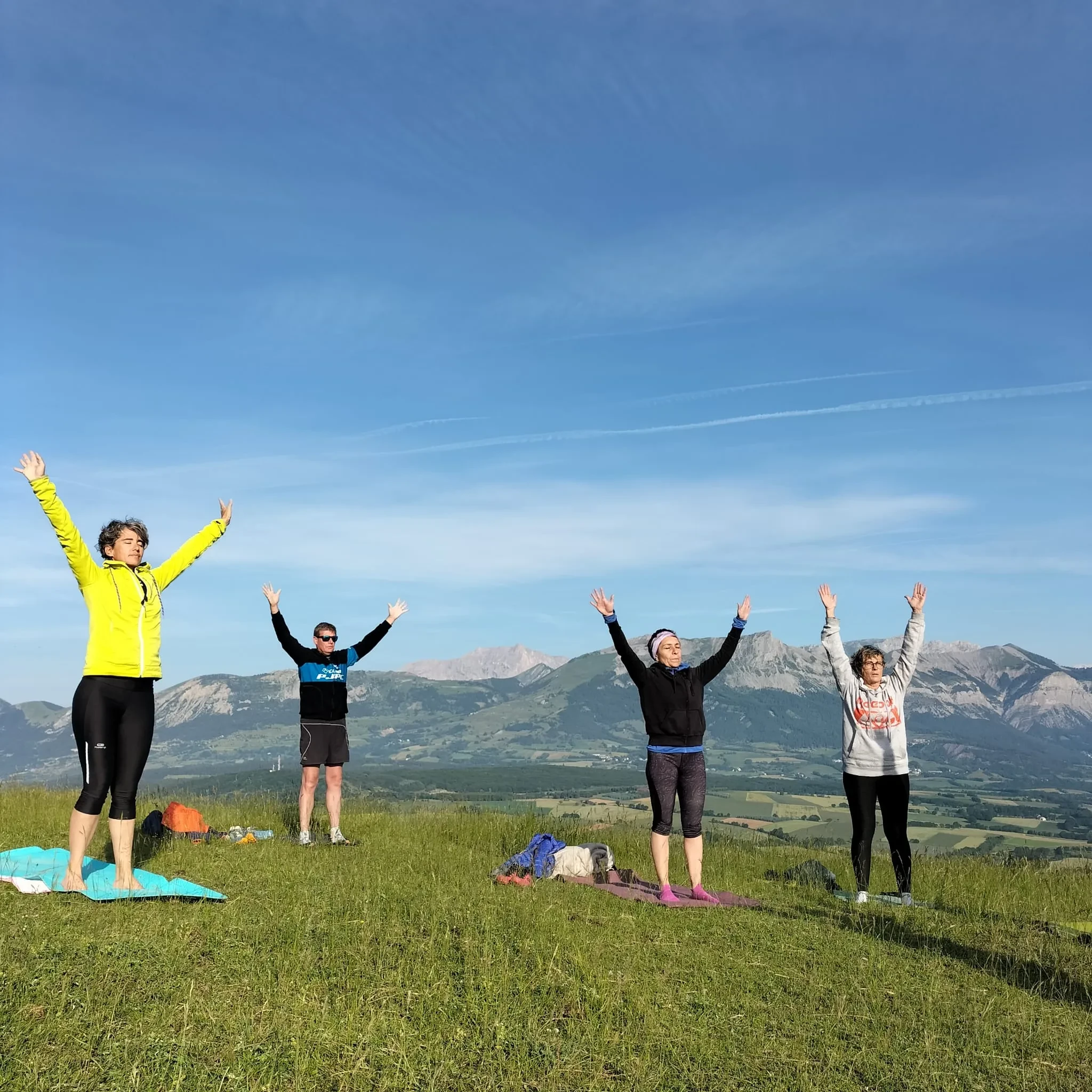 Quatre personnes faisant du yoga en montagne.